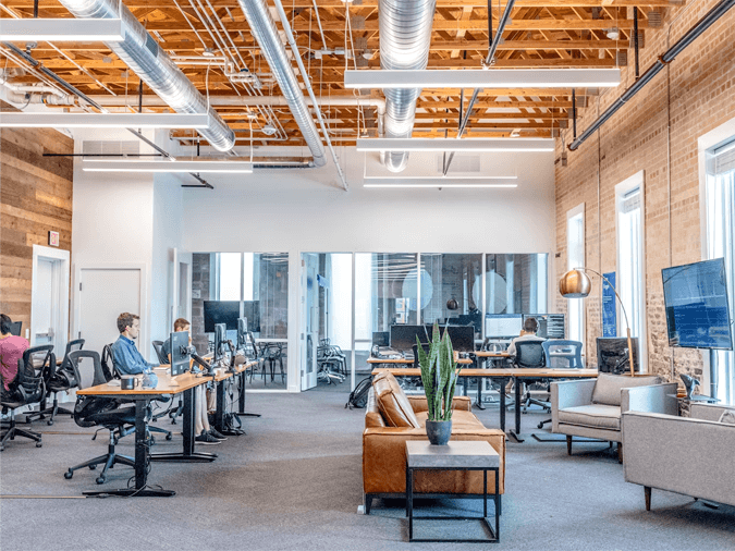 A modern open-plan office interior with people working at desks